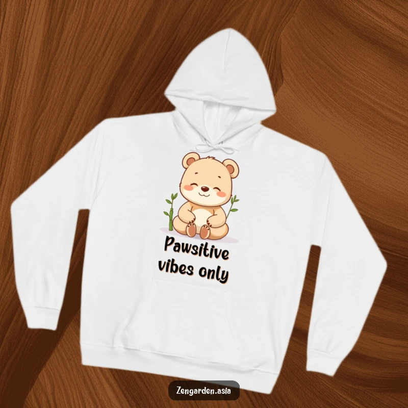 Funny meditating bear cub hoodie, deeply relaxed with eyes shut, a small bamboo plant beside it, offering warmth and humor.